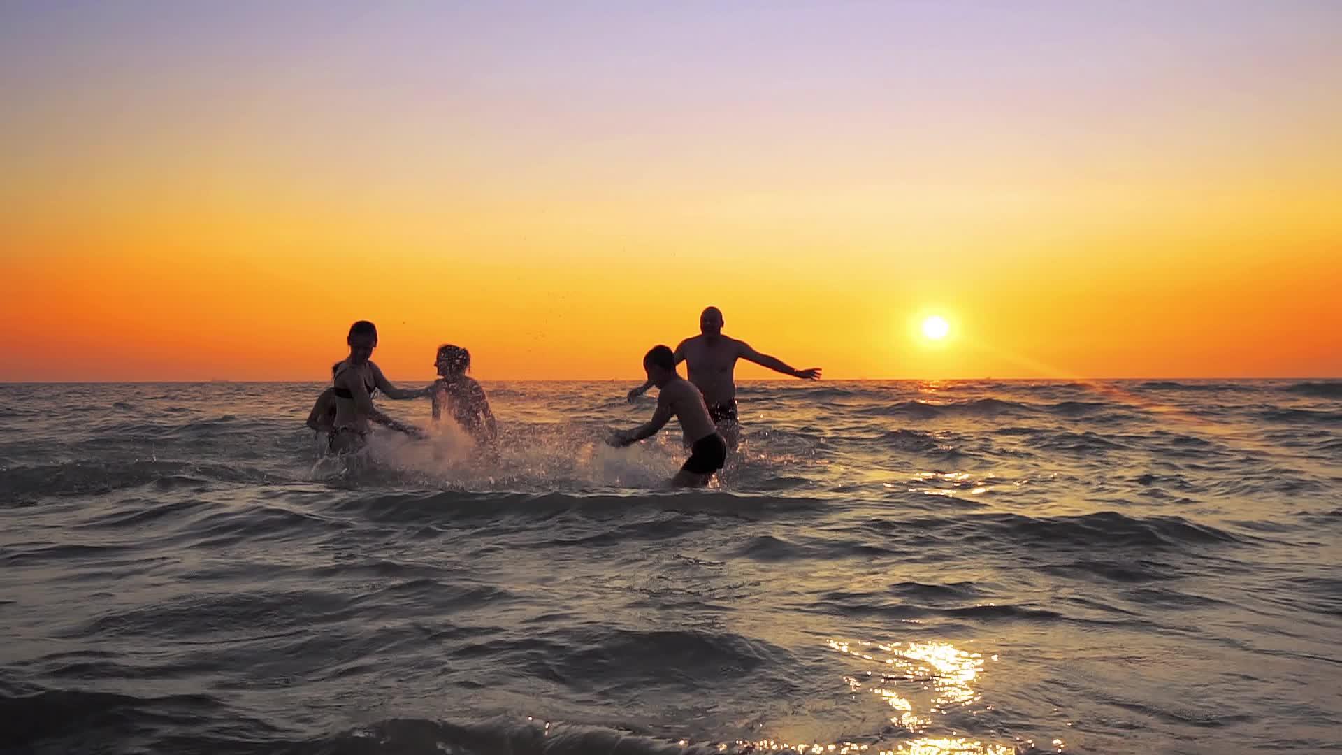 日落时在海中游泳在水中喷水拍电影和照片视频的预览图