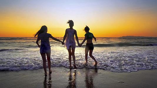 一群在日落的海滩上奔跑的人双手欢快地跳跃和喷洒视频的预览图