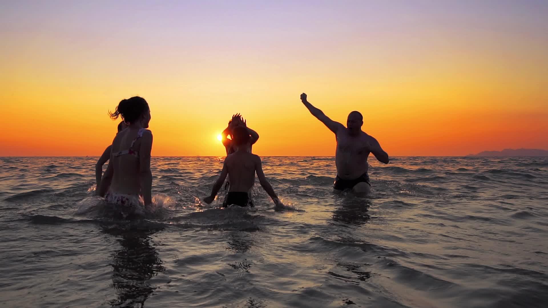 在夏天的海滩日落电影慢动作中家庭正在跳舞和跳跃视频的预览图
