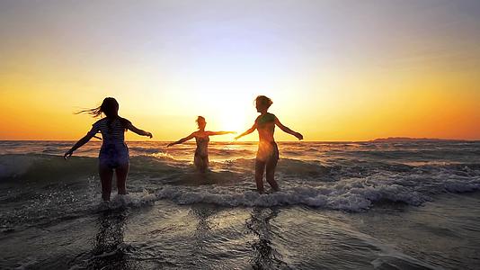 三个女孩在日落的海滩上跳舞庆祝慢动作视频的预览图