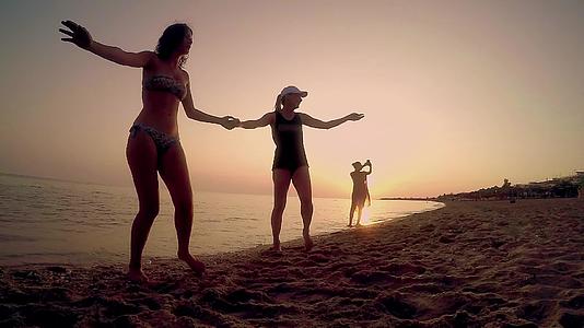 两个快乐的朋友在海滩上享受传统的民族舞蹈慢动作视频的预览图