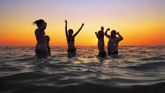 人们在海滩上日落时跳舞和喷洒青年欢乐派对视频的预览图
