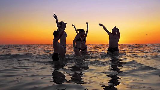 青年欢乐派对在海滩日落时跳舞和喷洒视频的预览图