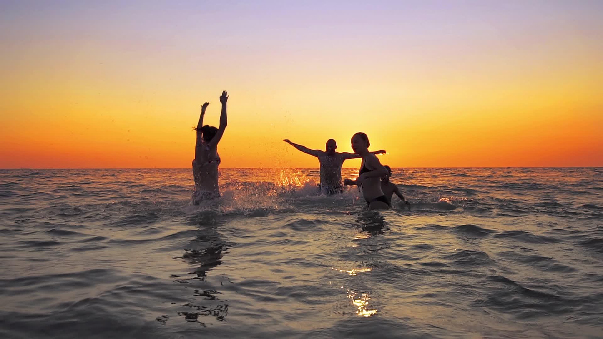 夏天海滩日落时家庭成员欢快地跳跃电影慢动作视频的预览图