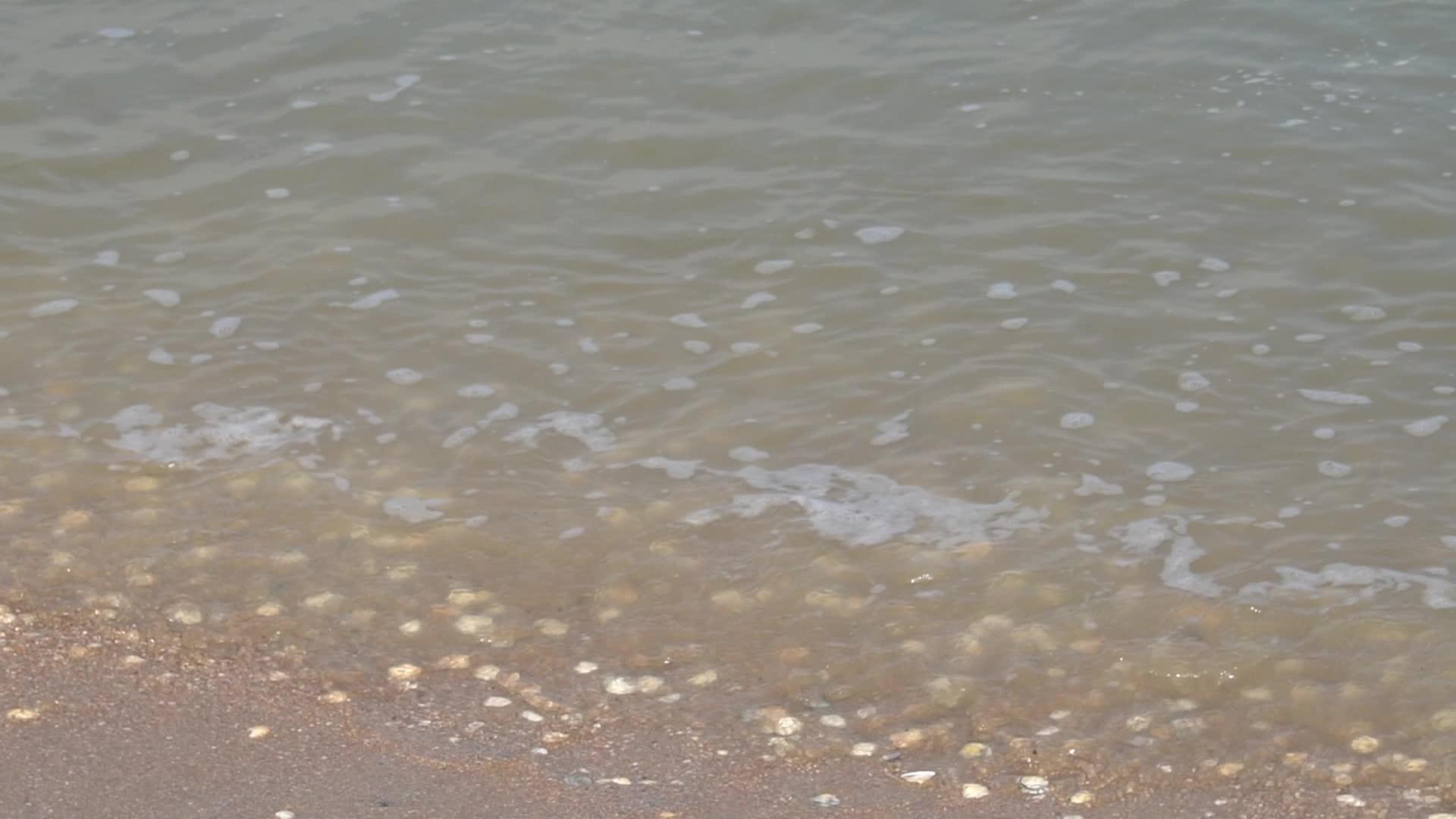 缓慢的运动和温和的波浪滚过沙滩视频的预览图