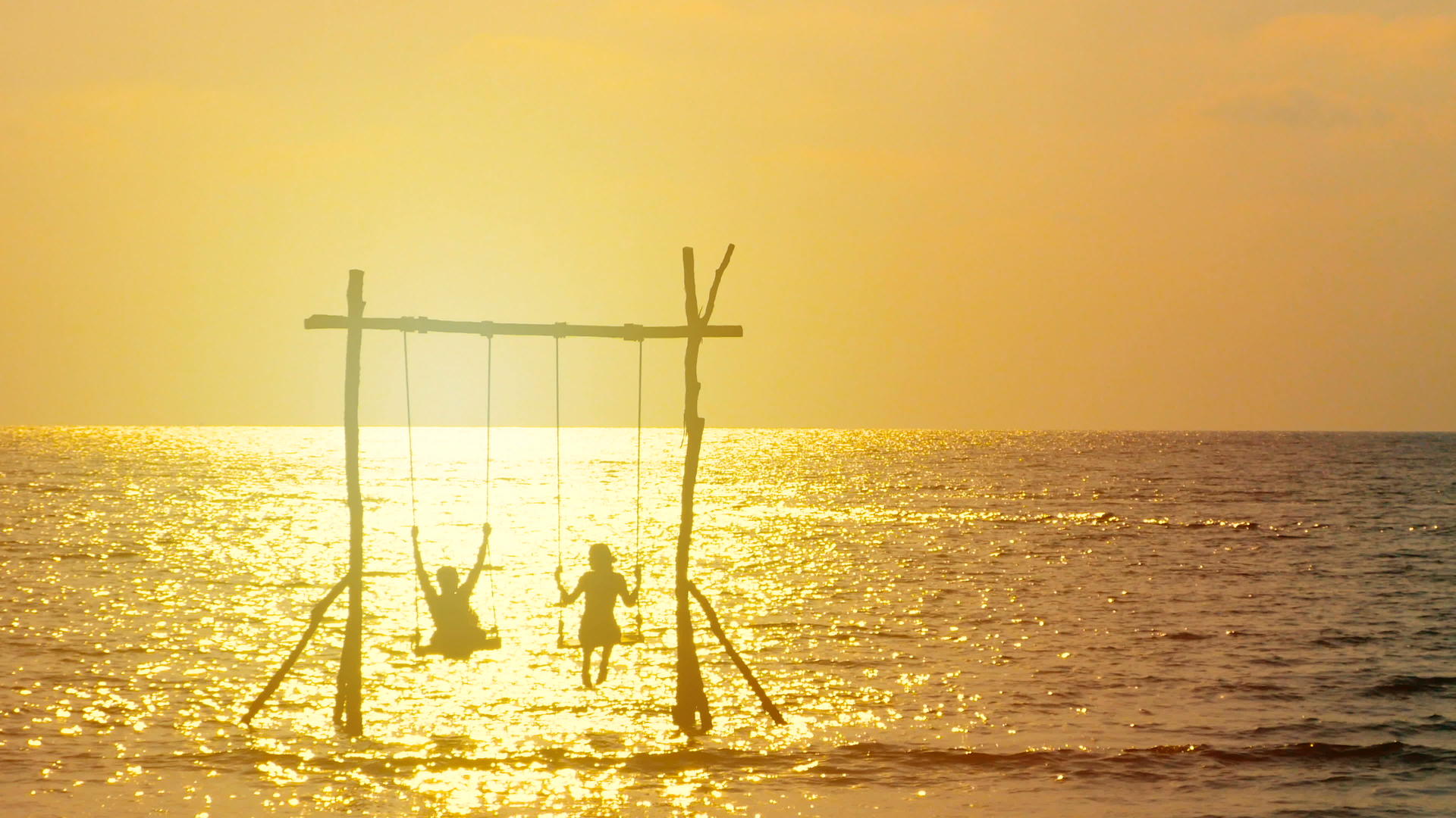 4K幸福夫妻的剪影喜欢日落时在海上荡秋千视频的预览图