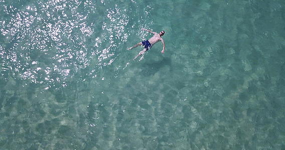 一架无人驾驶飞机射杀了一名在海里游泳的男子绿色和绿色的石头是清澈的视频的预览图