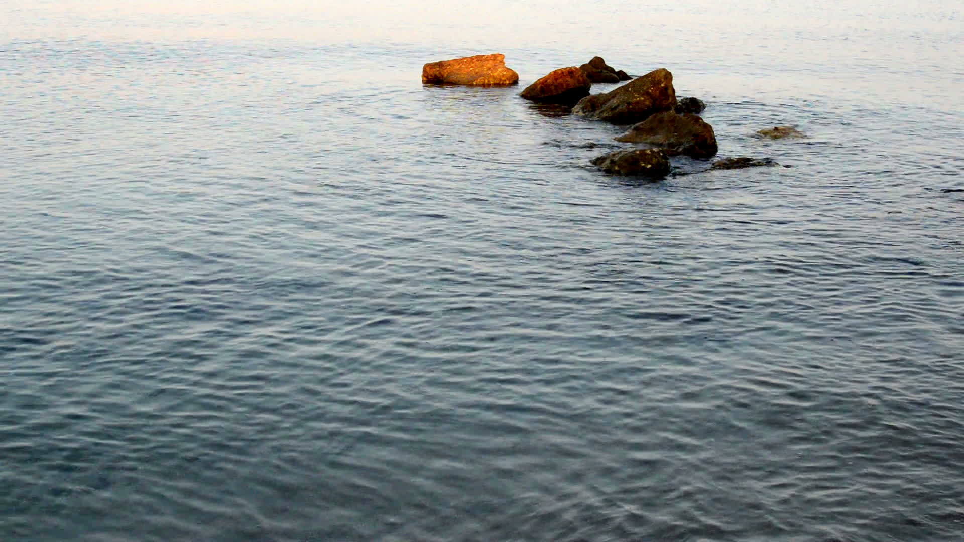 白色沙滩上岩石上的小海浪视频的预览图
