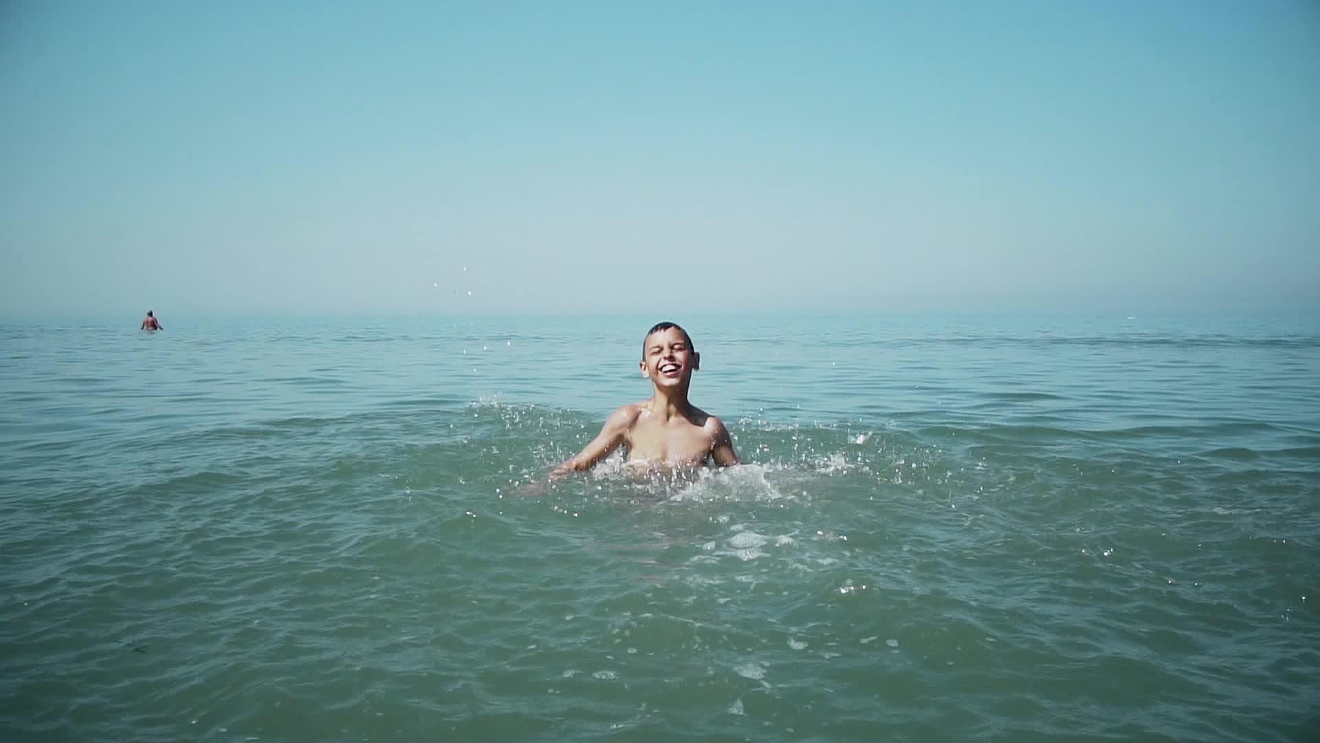 快乐的男孩在热带度假胜地海滩上喷洒绿水视频的预览图