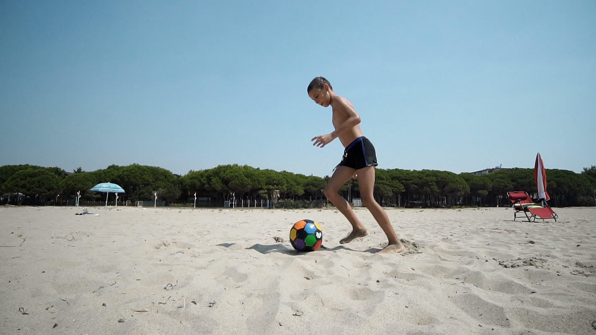 海滩上的小男孩玩足球、足球和慢动作视频的预览图