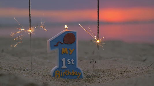 蜡烛和两个火花的慢动作站在海滩上面对模糊的海滩视频的预览图