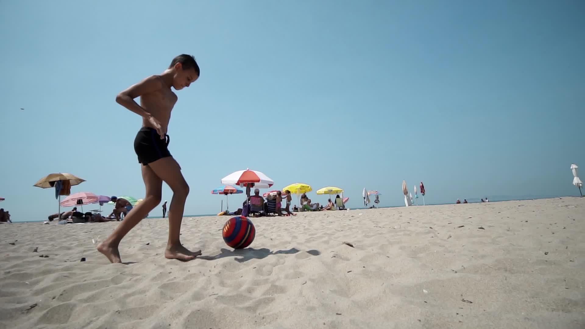 快乐的男孩在海滩上快乐地踢足球视频的预览图