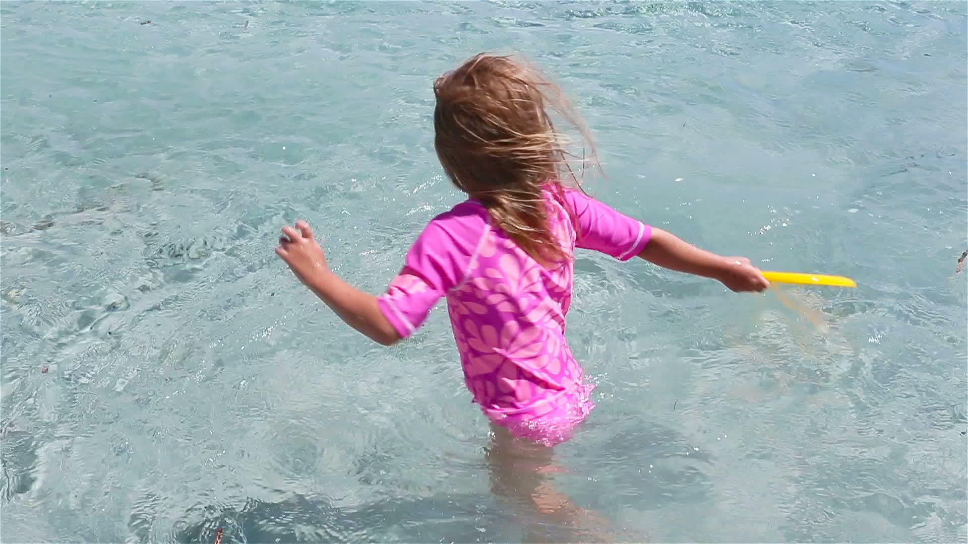 可爱的小女孩在热带度假期间玩飞盘孩子们在浅水中玩耍视频的预览图