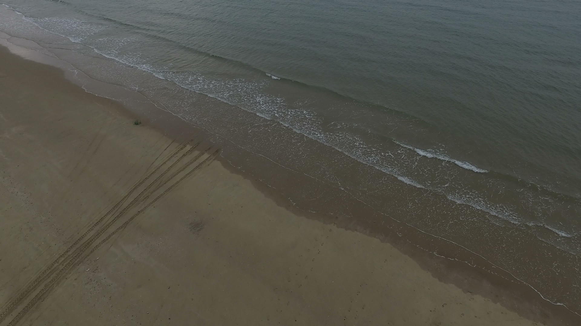 从海滩到海洋边缘的轮胎轨道视频的预览图