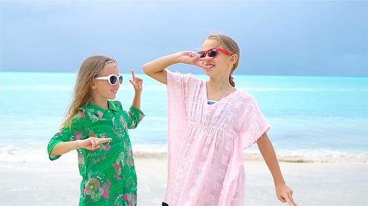 这个可爱的小女孩在热带海滩上玩得很开心背景是碧水和蓝天视频的预览图