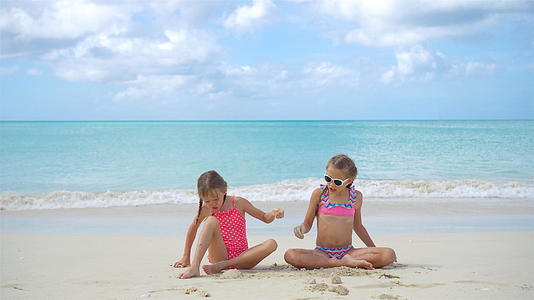 两个快乐的小女孩在热带海滩上玩沙子视频的预览图
