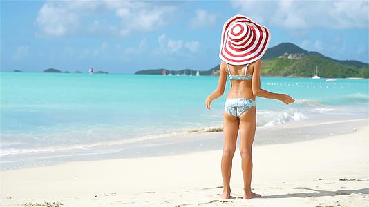 可爱的小女孩戴着大帽子在白色海滩上散步视频的预览图