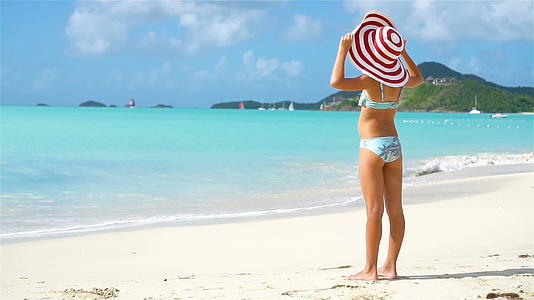 可爱的小女孩戴着大帽子在白色海滩上散步视频的预览图