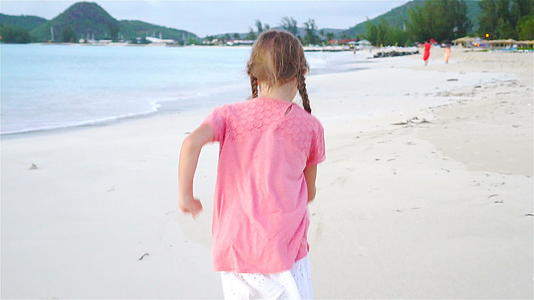 可爱的小女孩在海滩上快乐地奔跑孩子们享受暑假慢动作视频的预览图