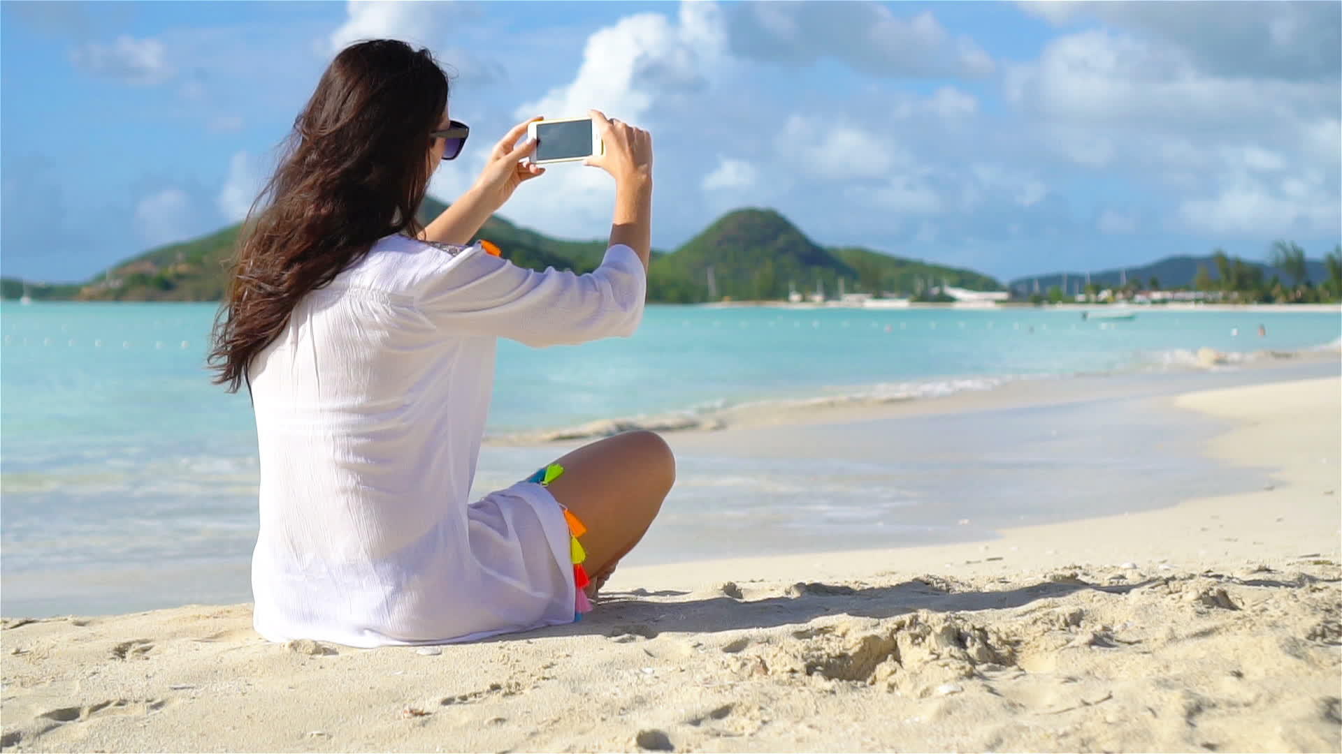 年轻女孩躺在白沙上用手机说话视频的预览图