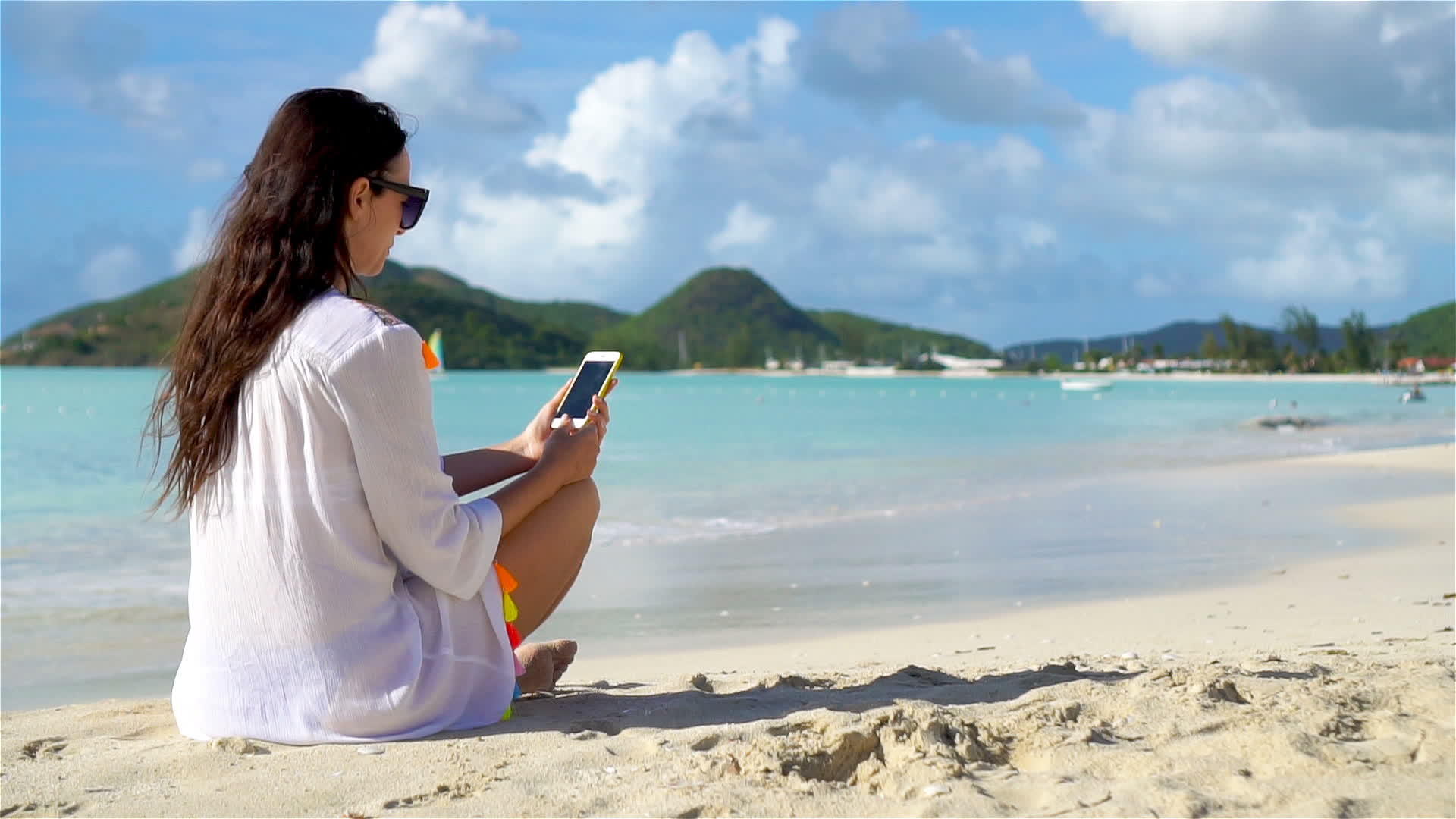 热带海滩上有电话的年轻女性视频的预览图
