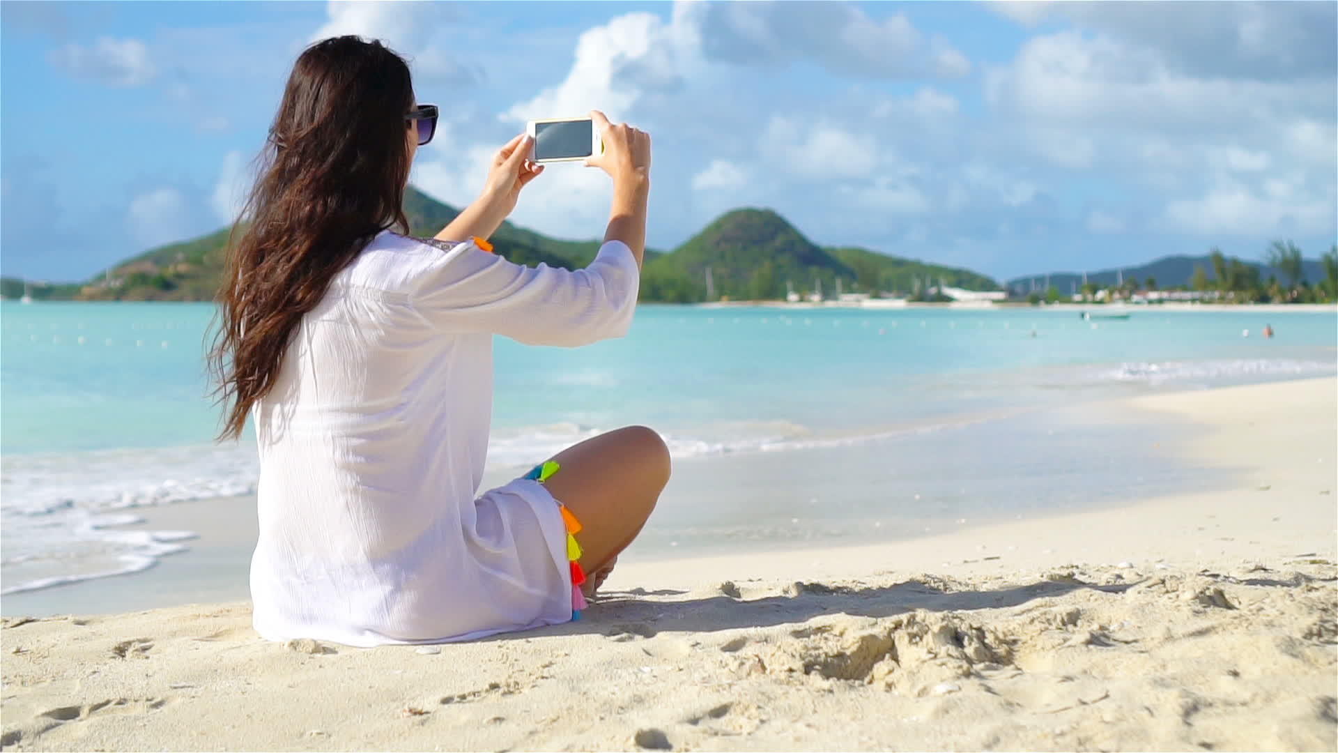 热带海滩上有电话的年轻女性视频的预览图