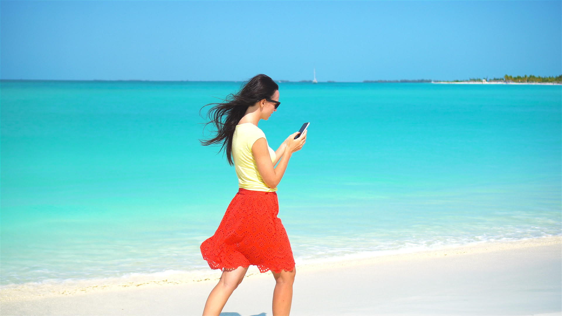 年轻女性在热带海滩度假期间使用移动智能手机视频的预览图