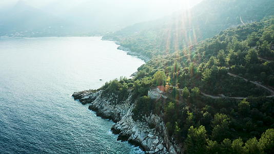 无人机用美丽的绿松石海水飞越岩石海岸线上的房屋视频的预览图