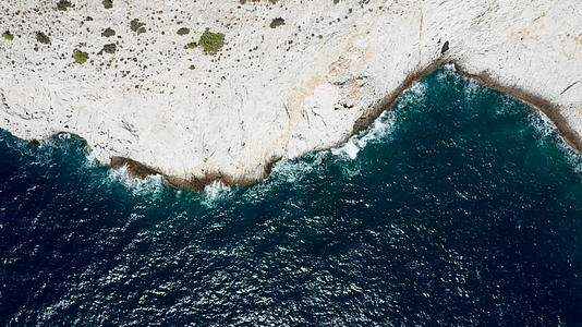 无人驾驶飞机拍摄的海浪冲入岩石海岸线的镜头视频的预览图
