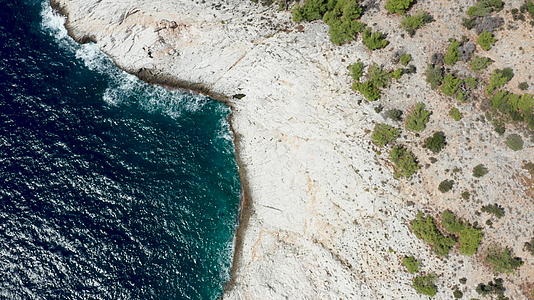 无人驾驶飞机沿着岩石海岸线和深海蓝色海洋飞行视频的预览图