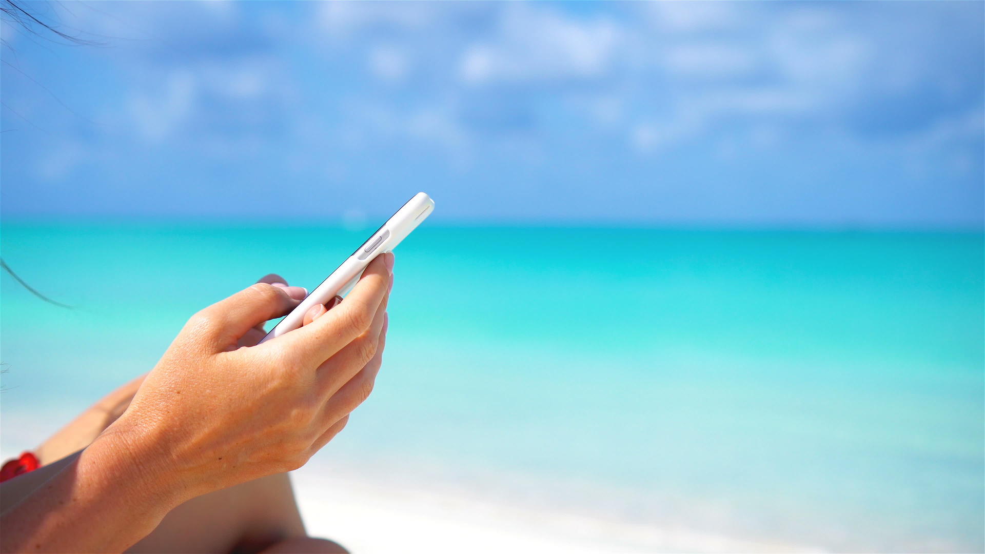 年轻女性在热带海滩度假时使用手机电话闭合智能手机视频的预览图