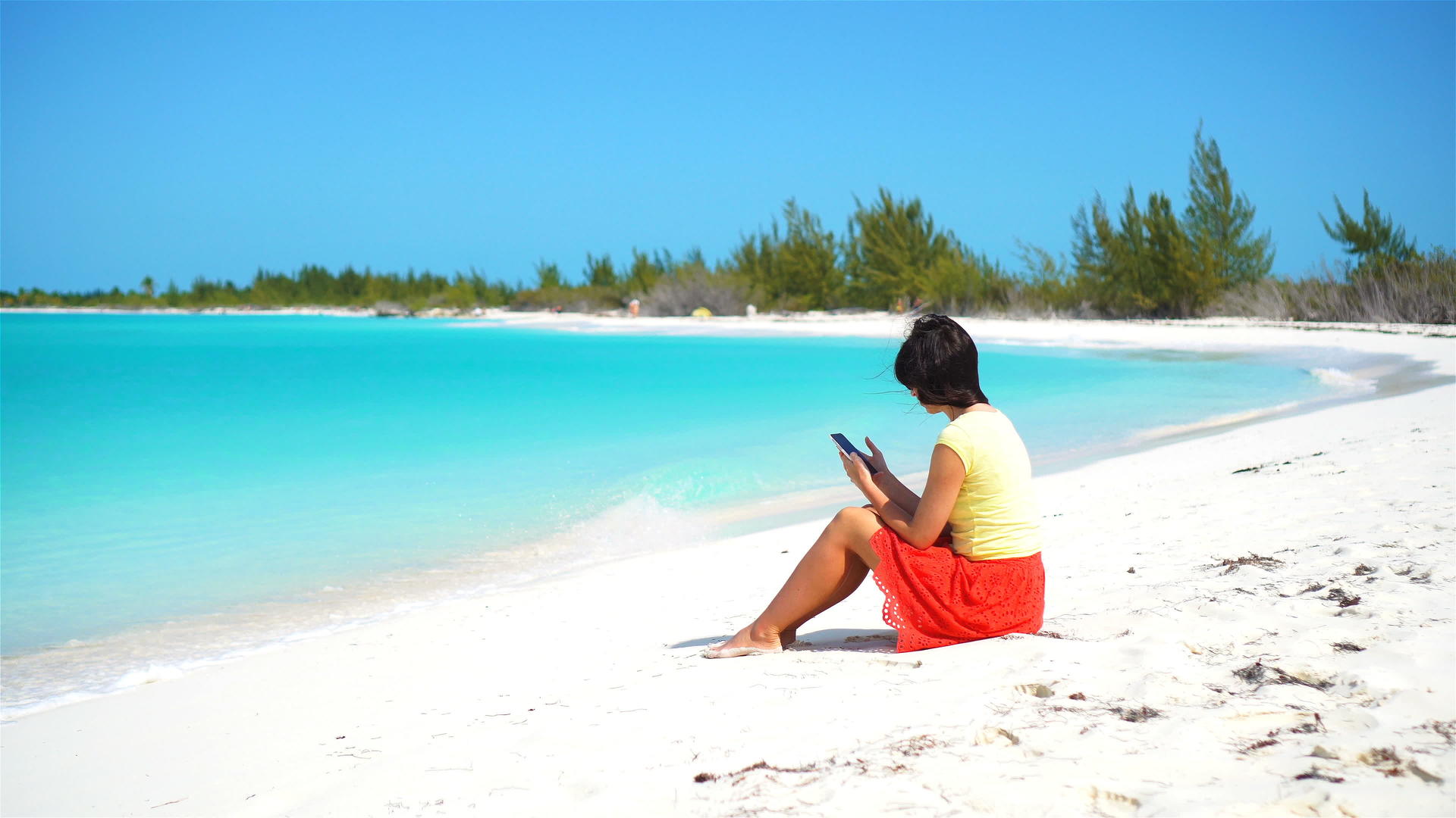 在热带海滩度假期间年轻女性带着手机游客使用移动智能手机视频的预览图