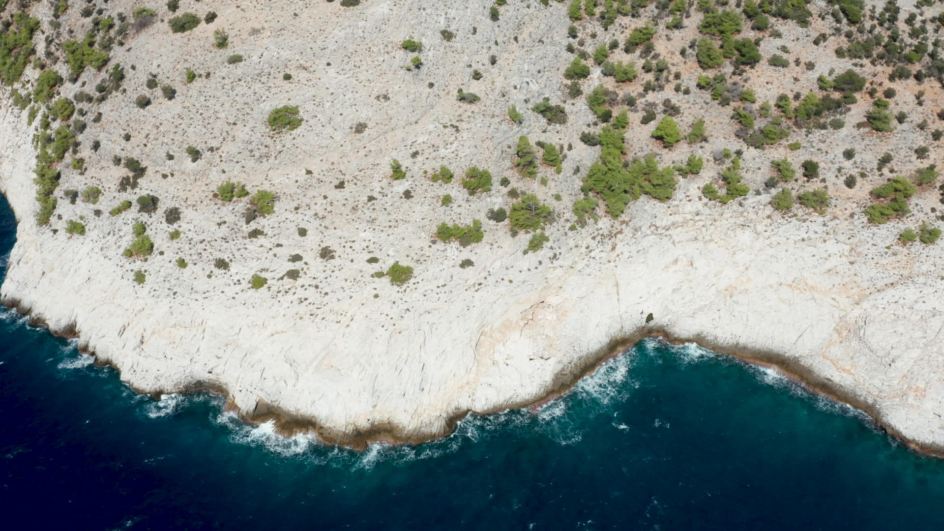 无人驾驶飞机以深蓝色的海水飞越岩石海岸线视频的预览图