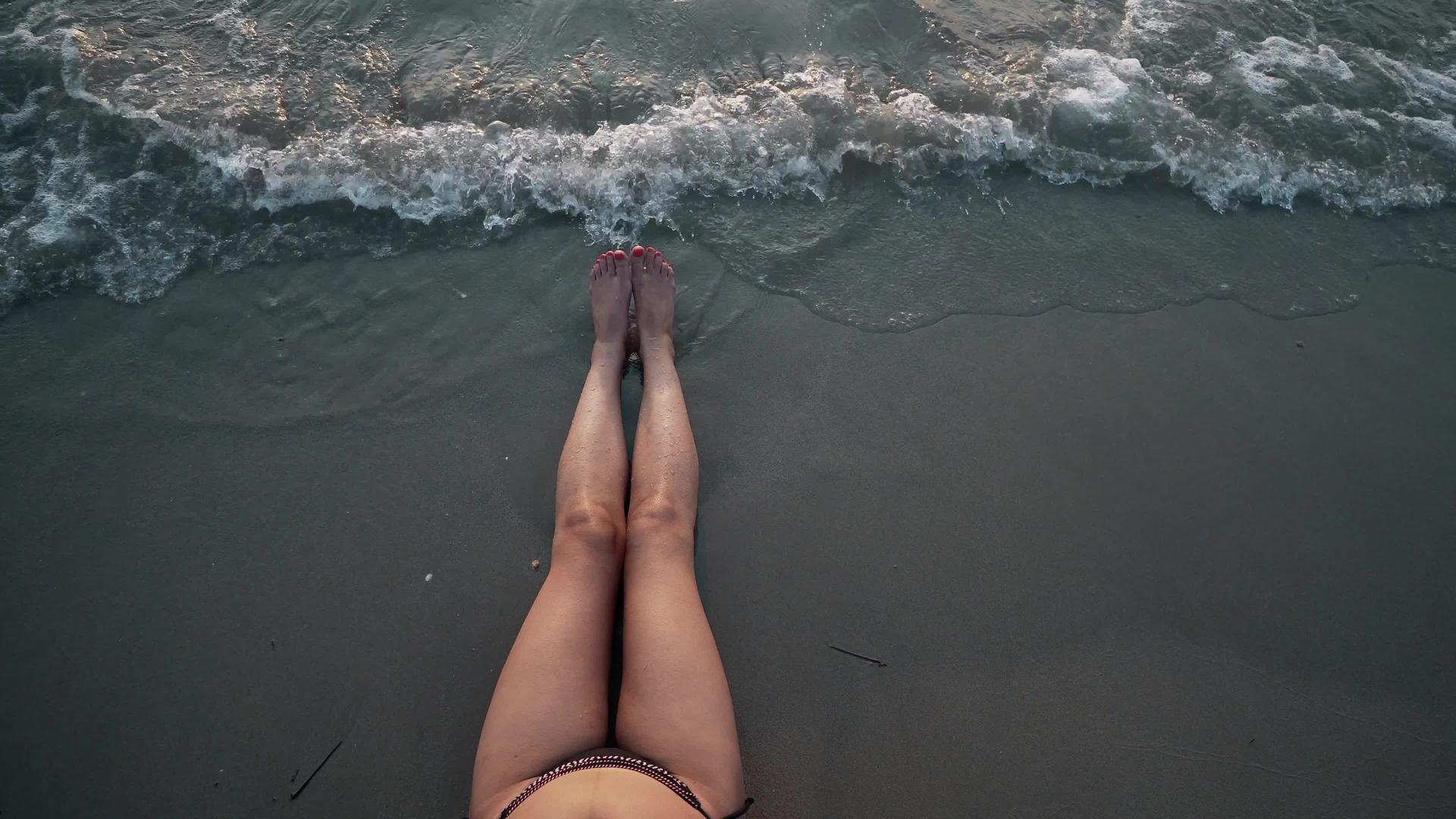 一个穿着比基尼的性感女人躺在美丽的海滩上落时在清澈的海滩上视频的预览图