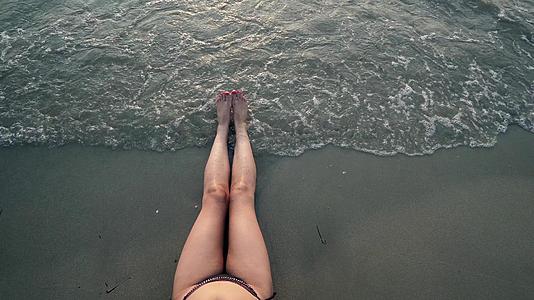 海滩上性感的腿在日落时喷洒海浪视频的预览图