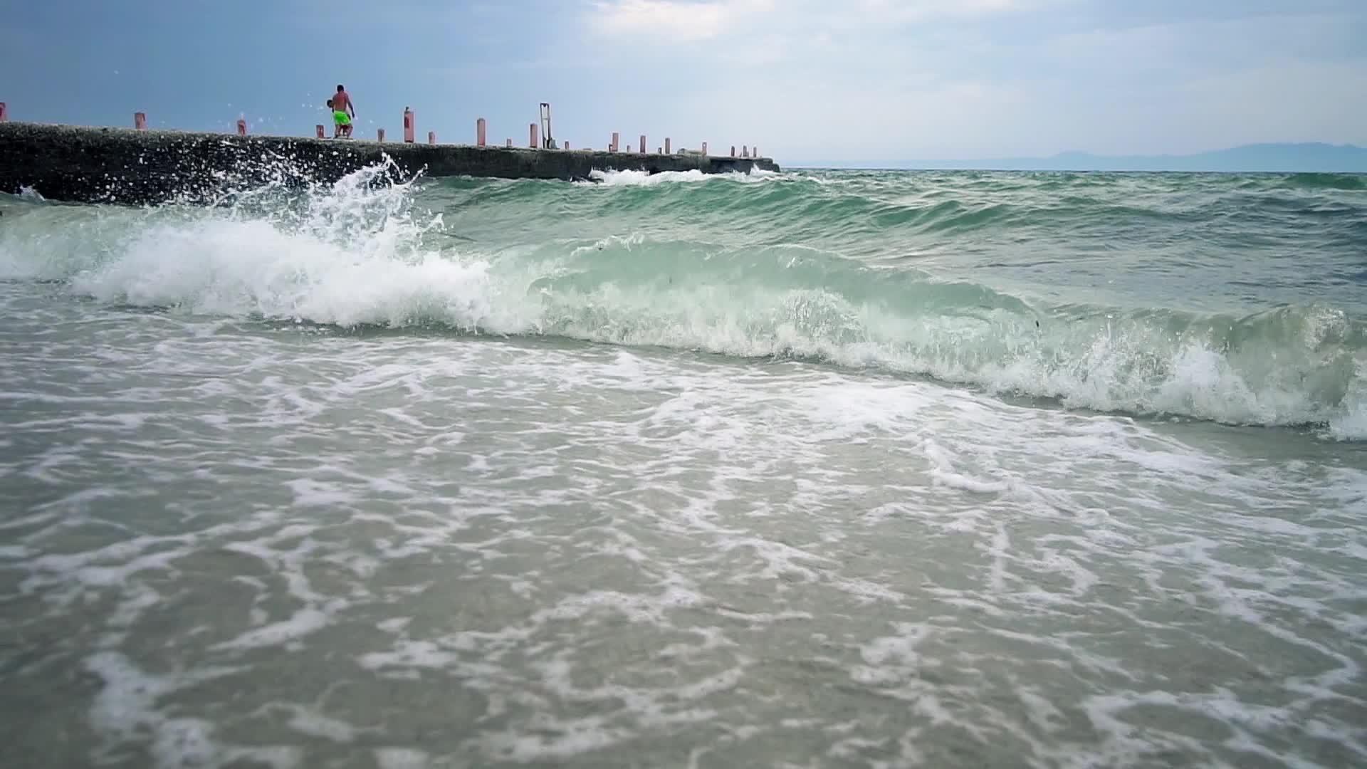 老码头在风浪和海浪中慢慢地喷在沙滩上视频的预览图