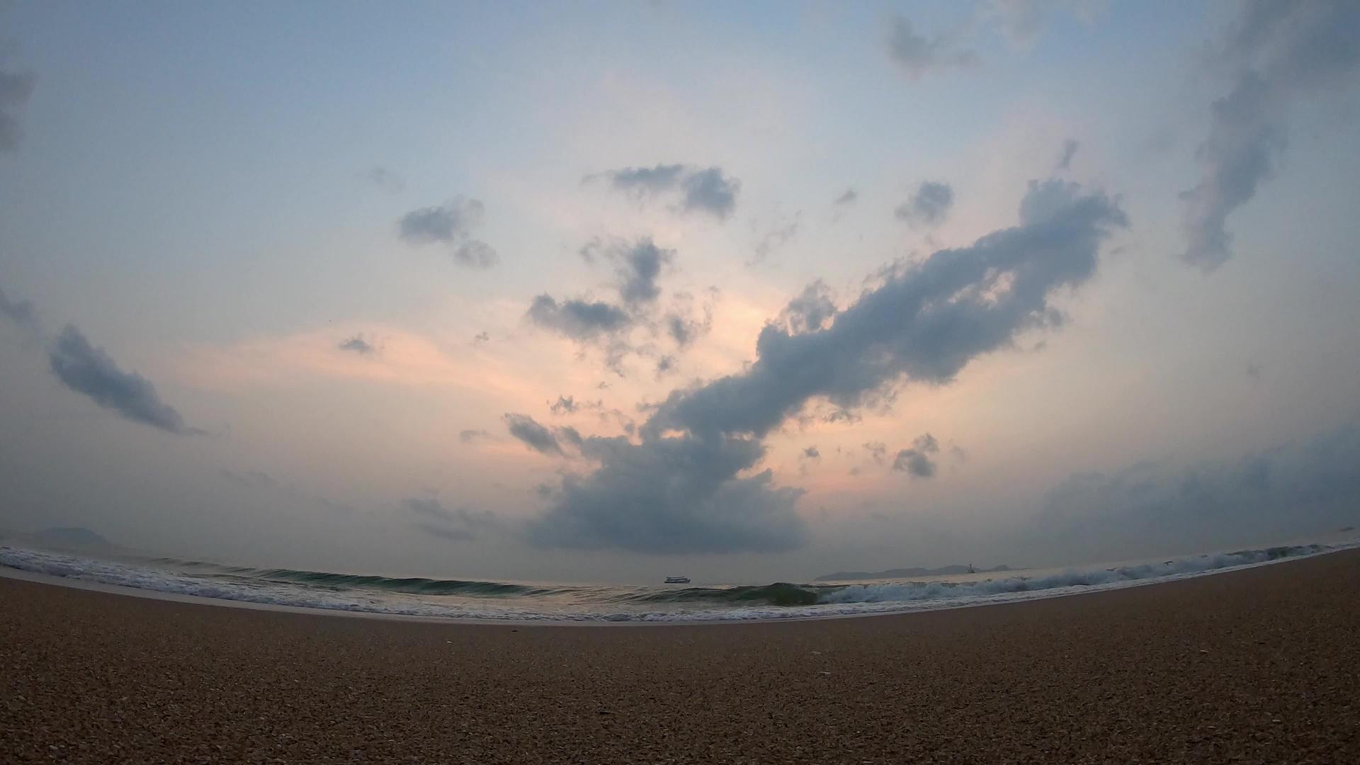 海浪撞击海滩船底部云层快速移动日出的金光照亮天空天空视频的预览图