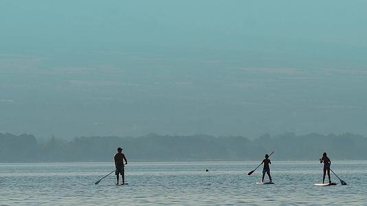 年轻人在美丽的湖海上垂直划桨SUP上做瑜伽视频的预览图