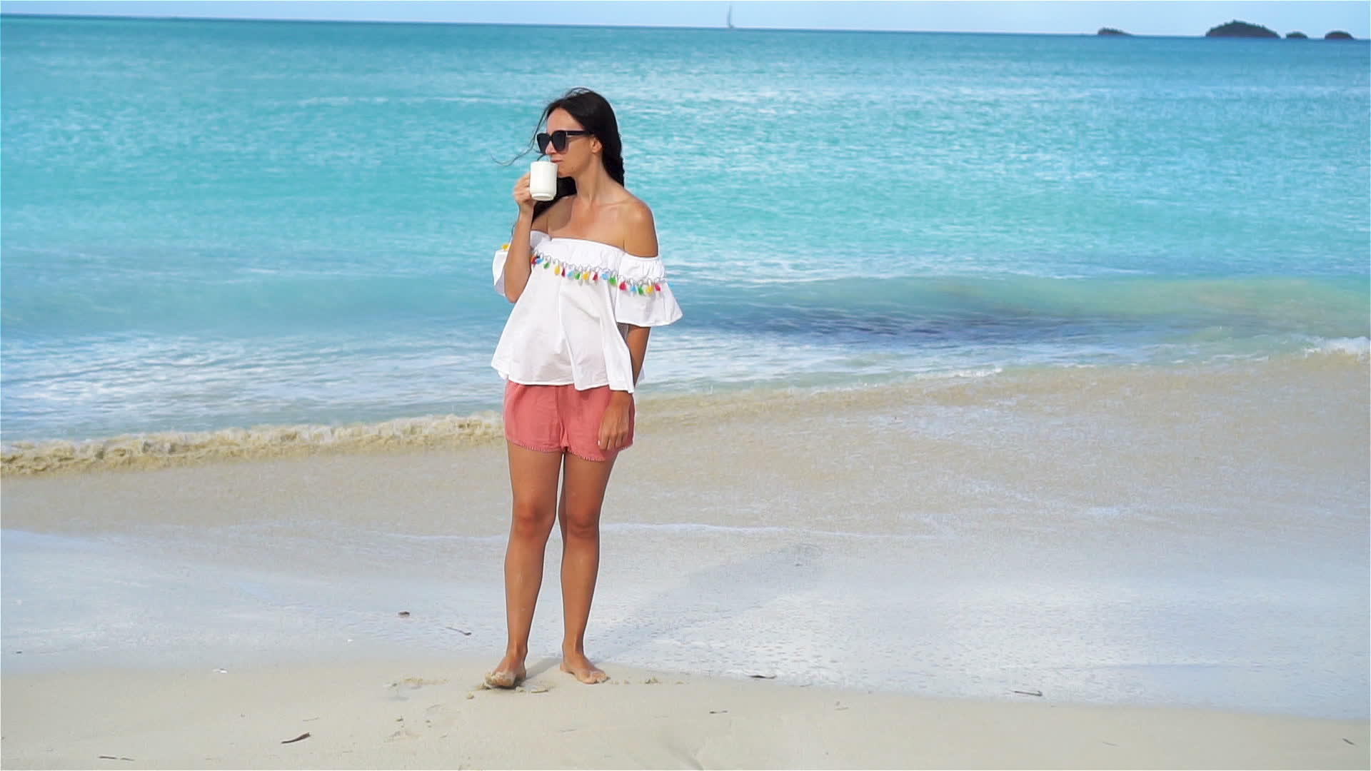 在白热带海滩上喝热咖啡的年轻女性慢动作视频的预览图
