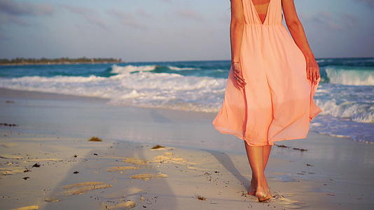 在白色的海滩上一个美丽的女人在暑假里靠近女人的腿慢慢地移动视频的预览图