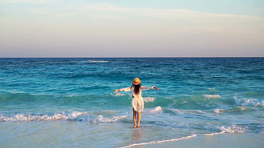 美丽的女人在白色海滩上的帽子背后的暑假快乐的女孩视频的预览图