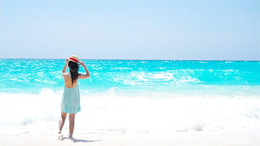 一个穿着夏装的女人在沙滩上的背影视频的预览图