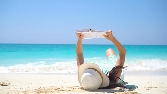 年轻女子在热带白色沙滩上阅读视频的预览图