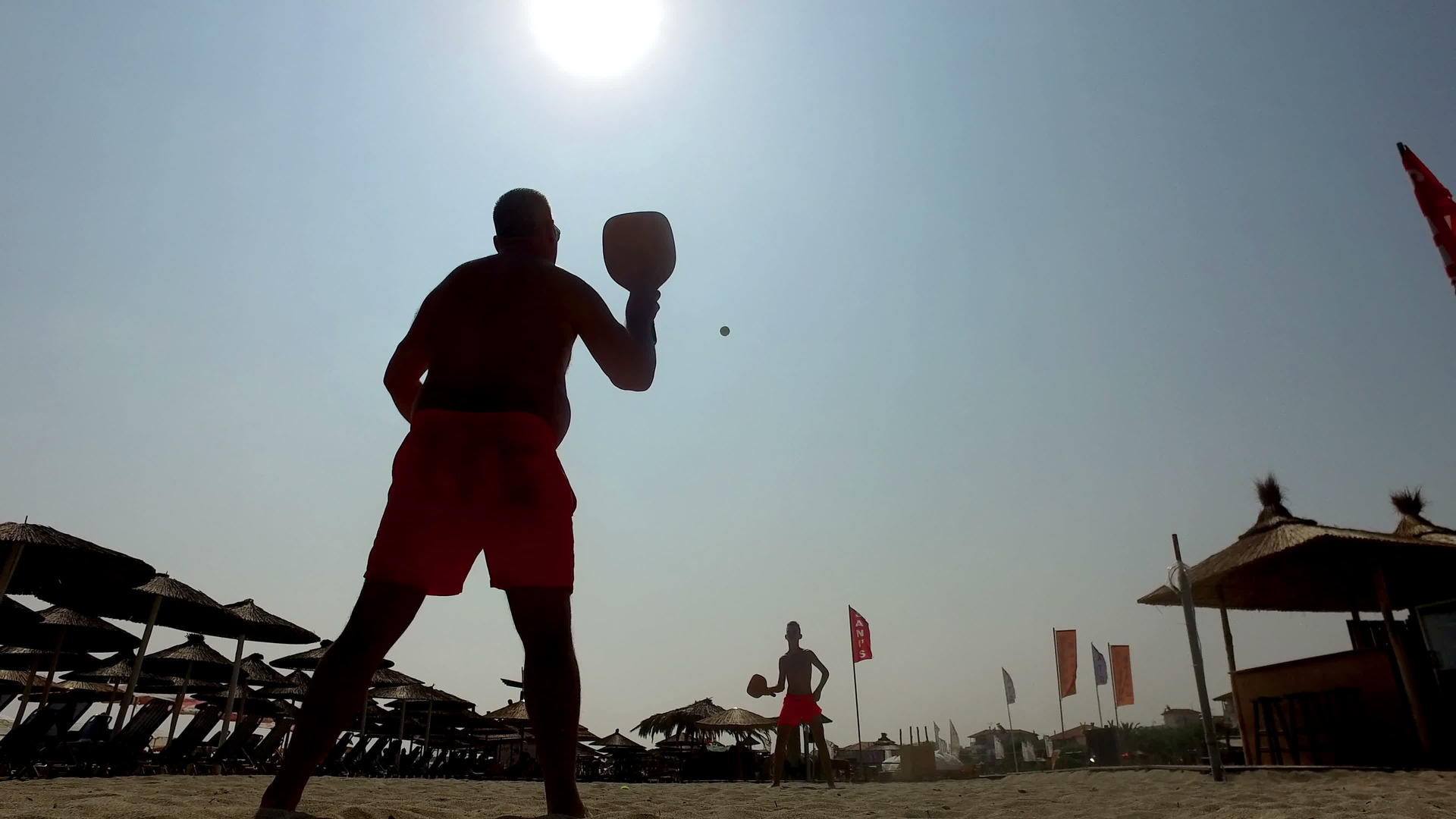 两个男人在沙滩上玩海滩网球视频的预览图