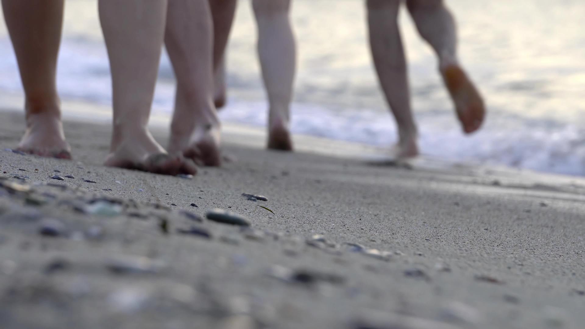 人们赤脚在海滩上行走海浪席卷着他们的脚和石头视频的预览图
