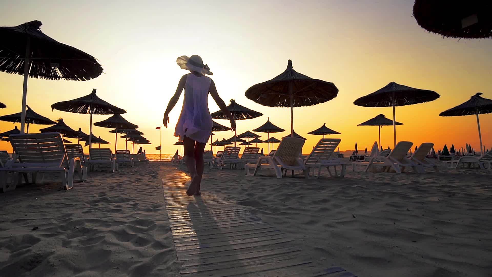 穿着白色连衣裙和帽子的妇女在海滩上度假视频的预览图