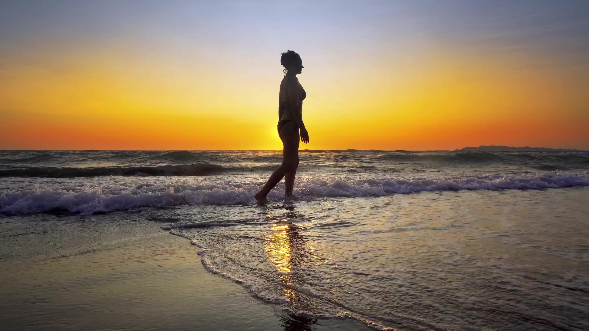 性感女性在日落时在水上行走Stadicam视频的预览图