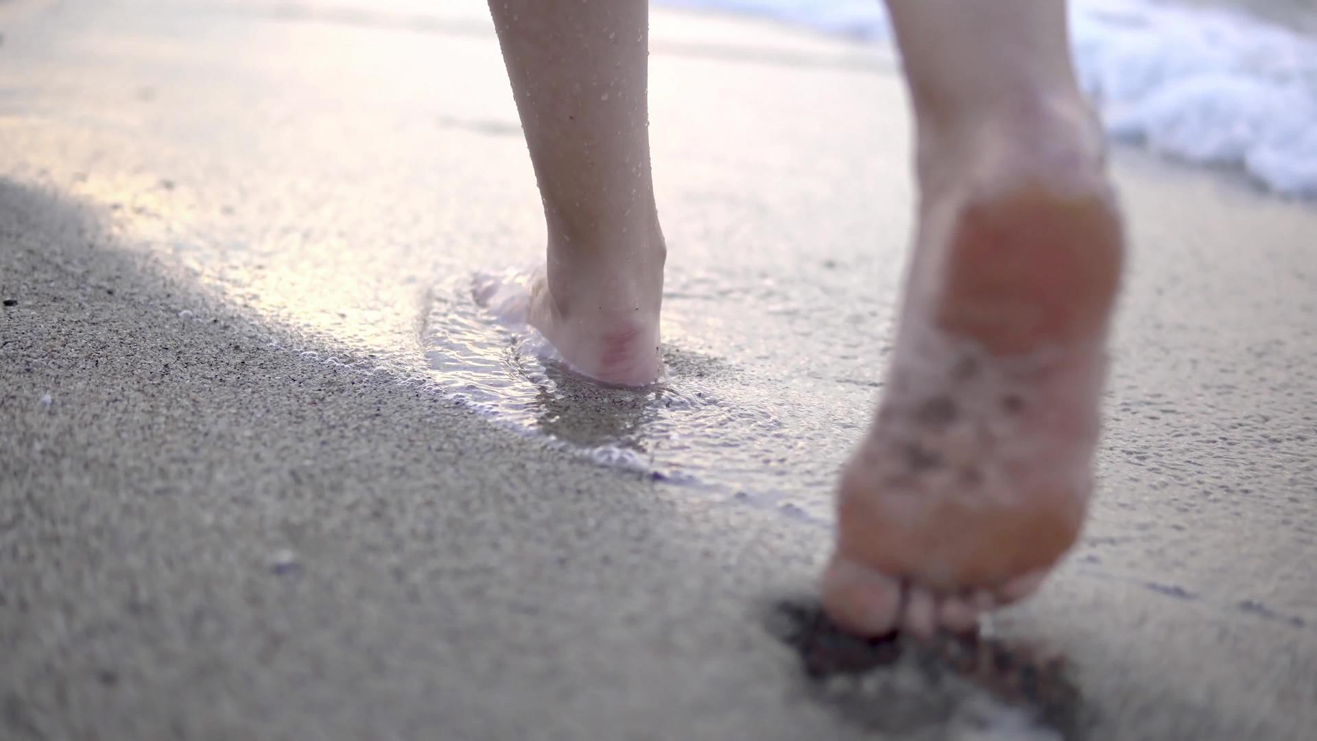 在海滩上旅行的女人在海滩上留下脚印女人的脚和金沙视频的预览图
