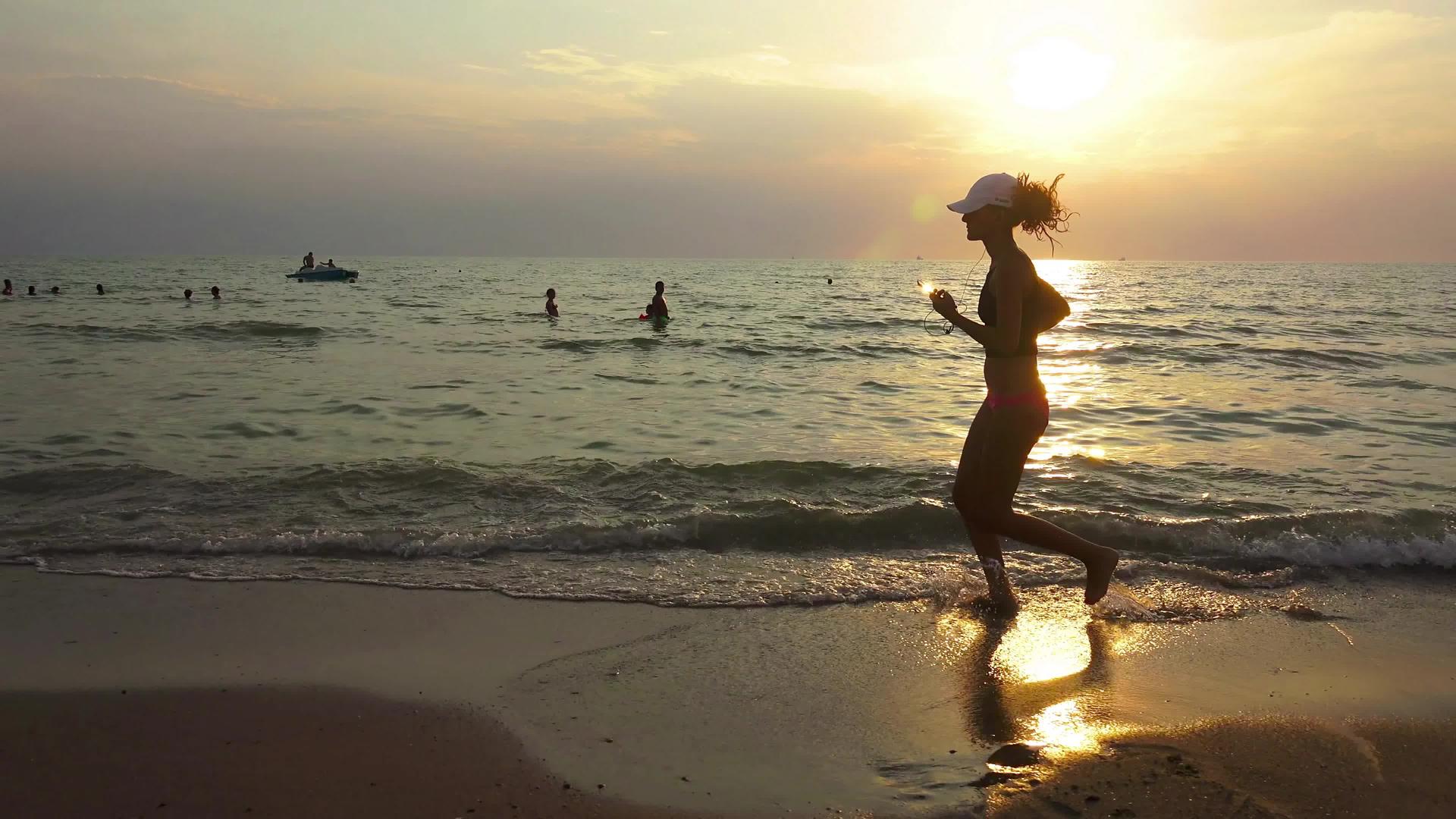 日出日落时戴着帽子的年轻性正在海上参加体操比赛视频的预览图