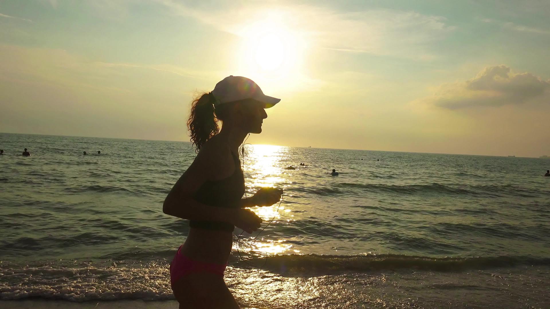 日出日落时戴着帽子的年轻性正在海上参加体操比赛视频的预览图